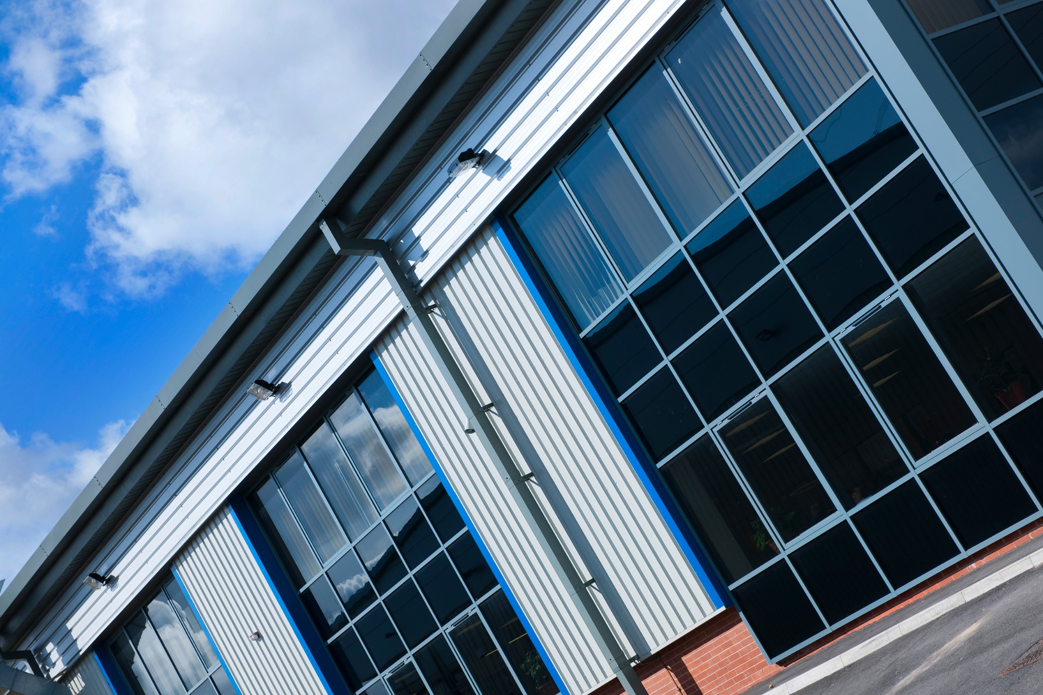 Detail of glazed bays, metal cladding and brick plinth