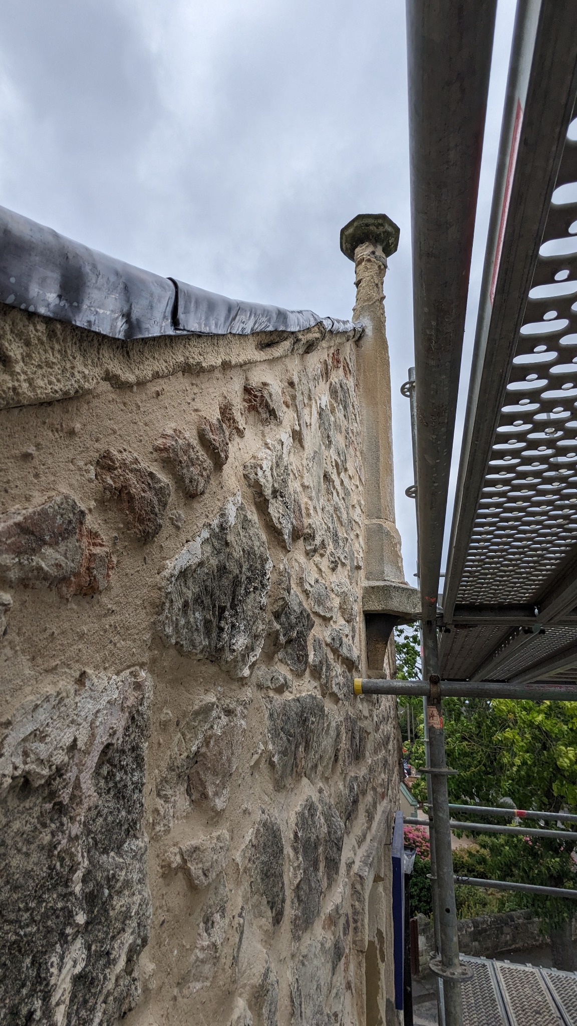 Repaired masonry and historic gable finial viewed from the scaffold